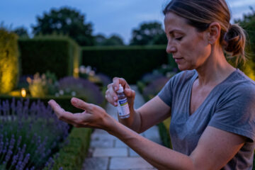 Illustration médicale réaliste d’une femme appliquant un répulsif anti-moustiques sur son avant-bras au crépuscule, dans un jardin français.